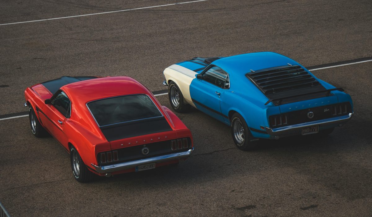 Two vintage Ford Mustangs parked on pavement in an outdoor setting.