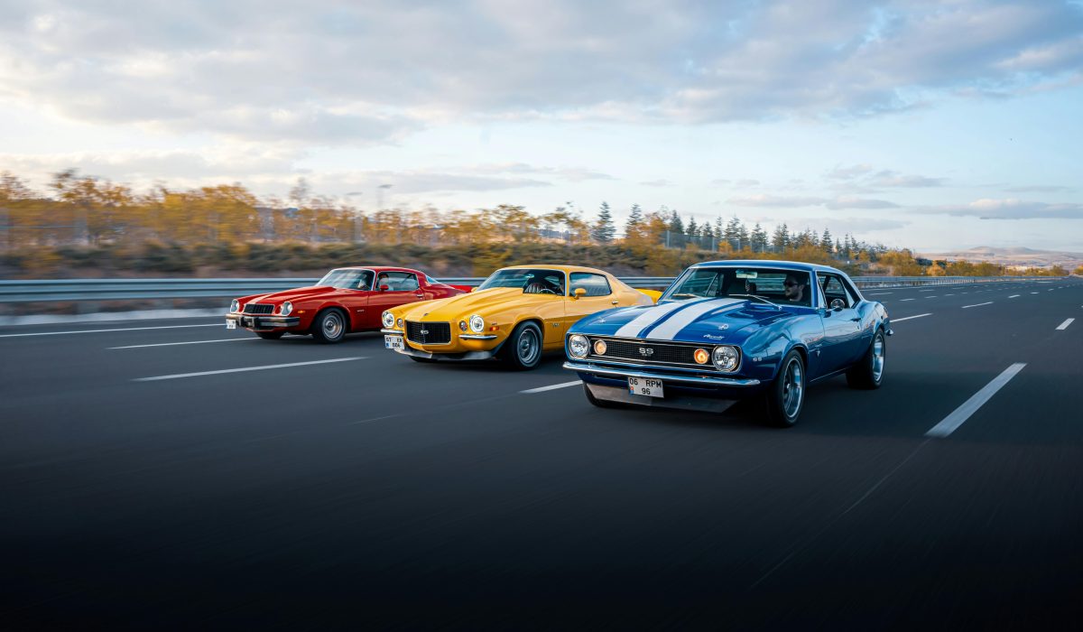 Three colorful classic muscle cars driving on a highway in Ankara, Türkiye.