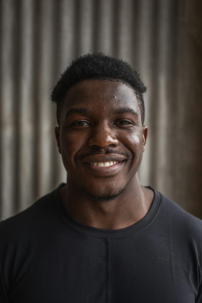 Portrait of a cheerful African American man smiling with a blurred gray background.