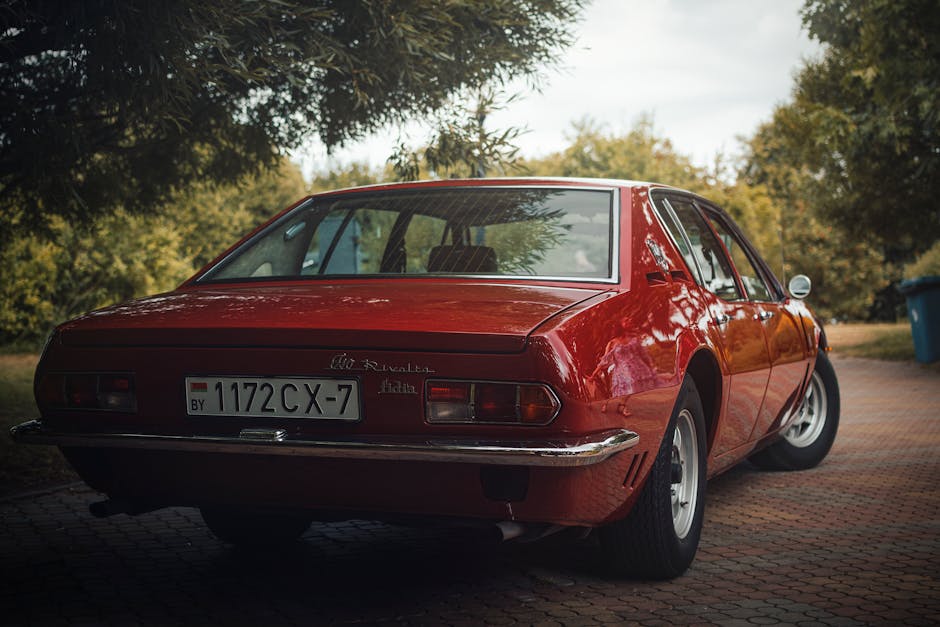 Vintage red car parked outdoors in Minsk, showcasing its classic design and shiny chrome details.